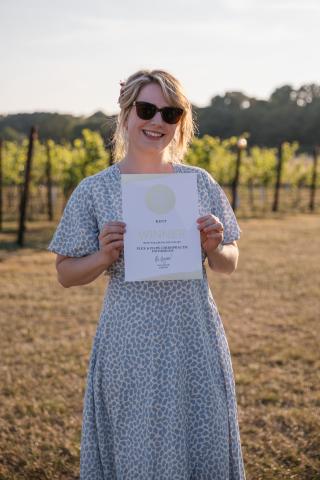 Jodie standing in a field holding a certificate